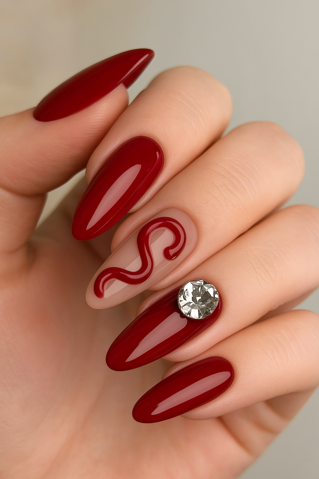 Glossy maroon press-on nails with crystal accent and red swirl design – luxury nail set by eLanto Nails, Pakistan