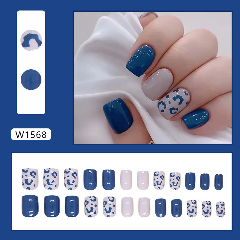 Nails showcasing a playful panther pattern in deep blue, complemented by a set of sleek solid blue nails.