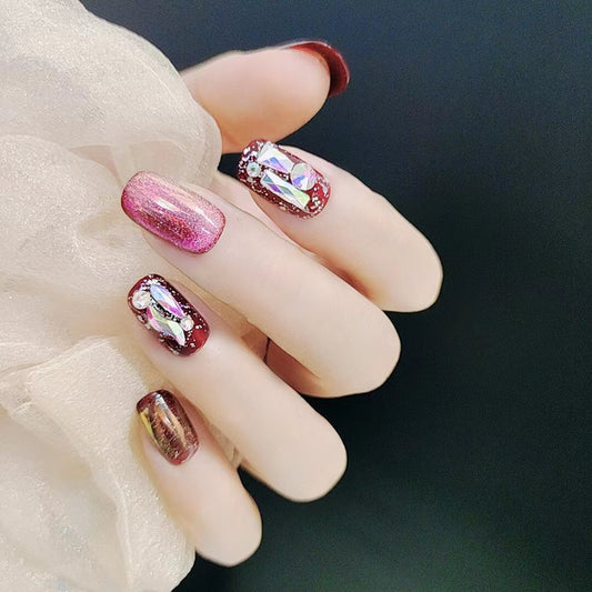 Diamond Ruby nails featuring a deep ruby red base adorned with sparkling diamond-like accents, creating a luxurious and glamorous look.