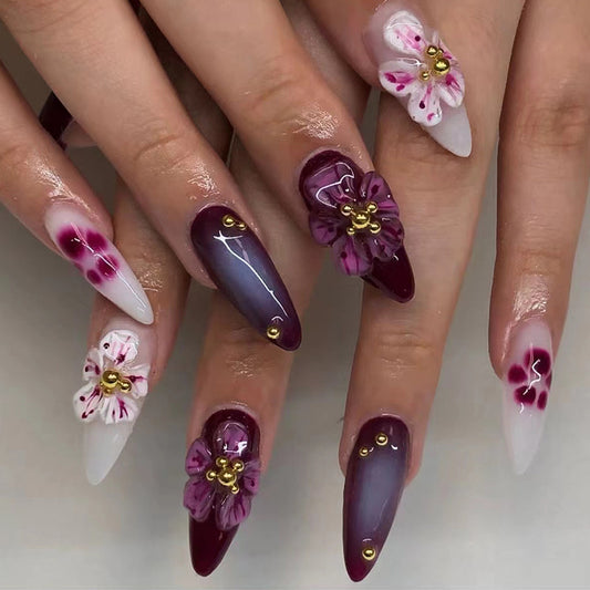 Almond-shaped plum floral nails featuring delicate floral designs in contrasting colors, creating a chic and elegant look.