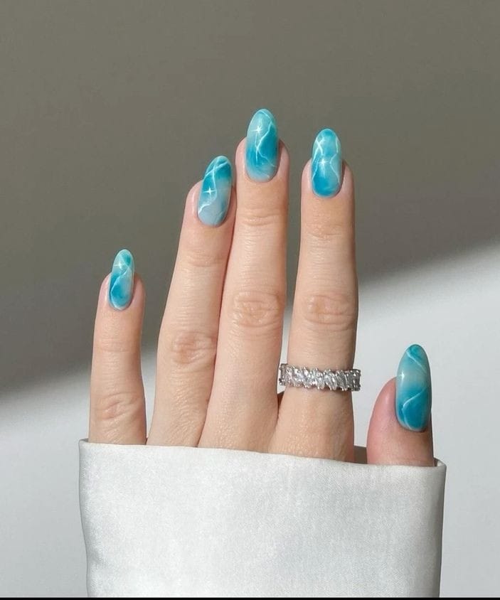 "Trendy marble blue nails featuring a stunning swirl pattern."