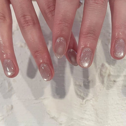 Elegant glossy ivory nails featuring a cat eye effect, creating a sophisticated look with a soft, radiant finish.