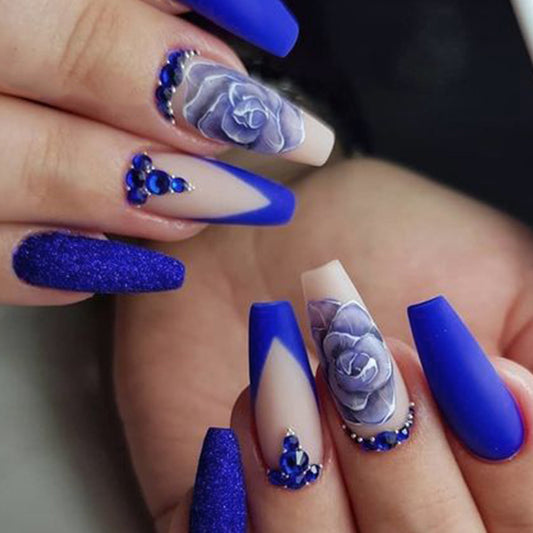 Beautiful coffin press on fake nails with the touch of royal blue solid nails and ivory nails having blue petals and stones on nails.